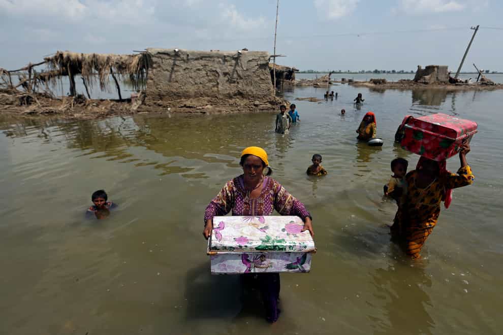Women carry belongings salvaged from their flooded home after monsoon rains, in the Qambar Shahdadkot district of Sindh Province in Pakistan (Fareed Khan/AP)