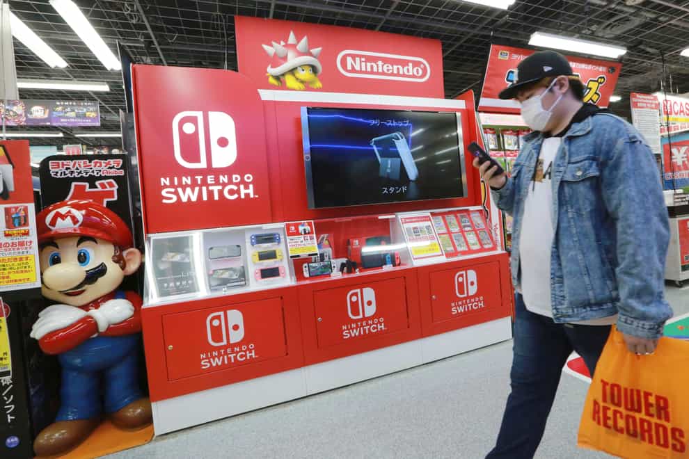 A man walks past an advert for Nintendo Switch at an electronics store in Tokyo (Koji Sasahara/AP)