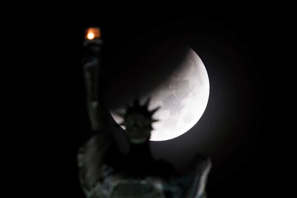 The Earth’s shadow passes in front of the moon during a lunar eclipse, as the statue of Lady Liberty atop the Liberty Building in downtown Buffalo, New York, does her part to light up the early morning sky on Tuesday November 8 2022 (Derek Gee/The Buffalo News/AP)