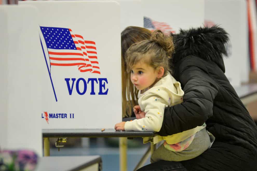 Emma Kent, two, looks around while her mother, Melinda, fills out her ballot at a polling location in Chesterfield, New Hampshire, during the midterm elections (Kristopher Radder/The Brattleboro Reformer via AP)