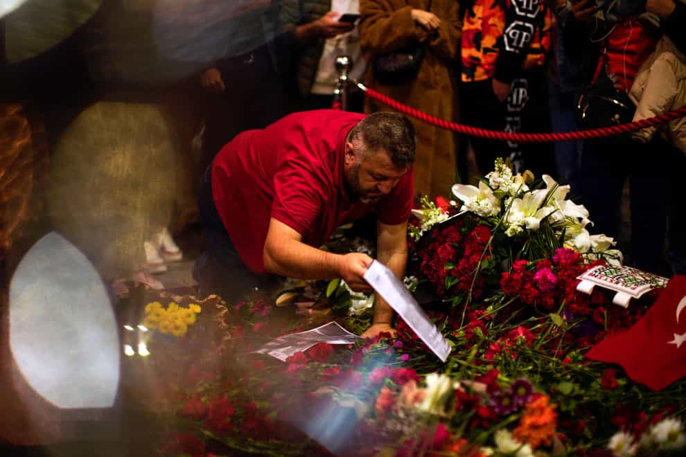 A man places flowers and photographs in the memorial spot of Sunday’s explosion on Istanbul’s popular pedestrian Istiklal Avenue in Istanbul (Francisco Seco/AP/PA)
