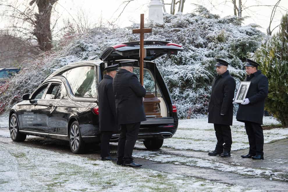 Pallbearers stand by the vehicle carrying the coffin of Boguslaw Wos (AP)