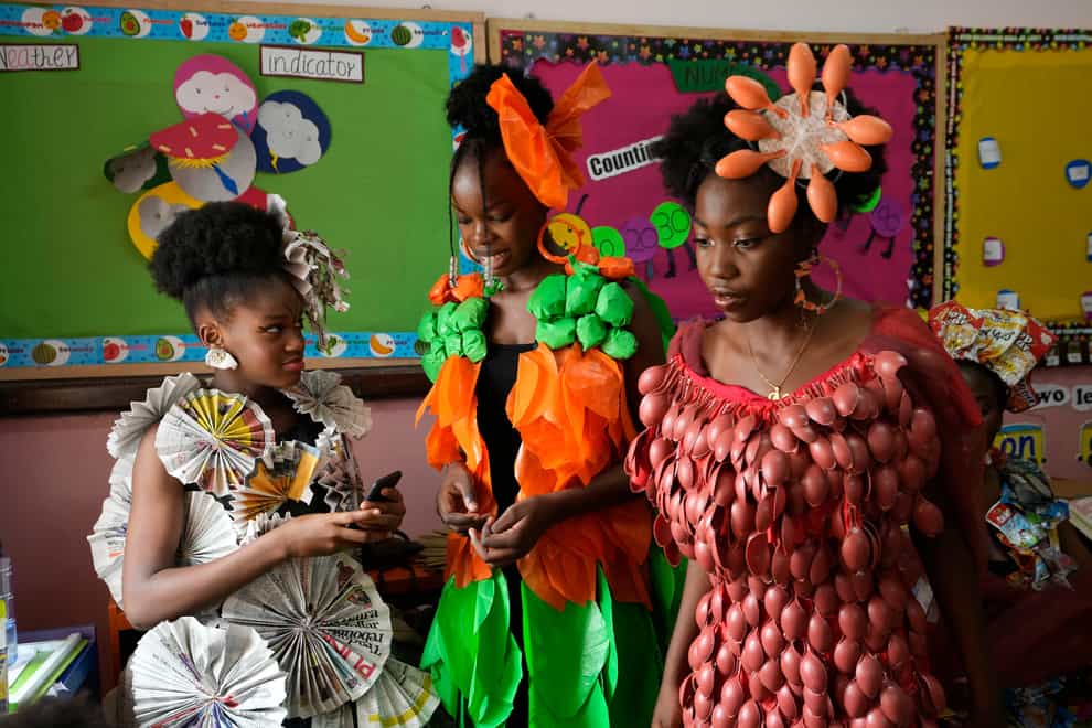 Jalokun Nifemi, left, wearing an outfit made from newspapers, Okpala Crystal, Center, wearing an outfit made from recycled plastic bags and Nathaniel Edegwa, right, wearing an outfit made from recycled plastic spoons, wait back stage before the ‘trashion show’ (Sunday Alamba/AP)