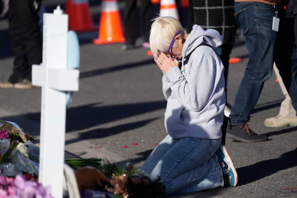 A mourner prays at a makeshift memorial following the shootings (AP)