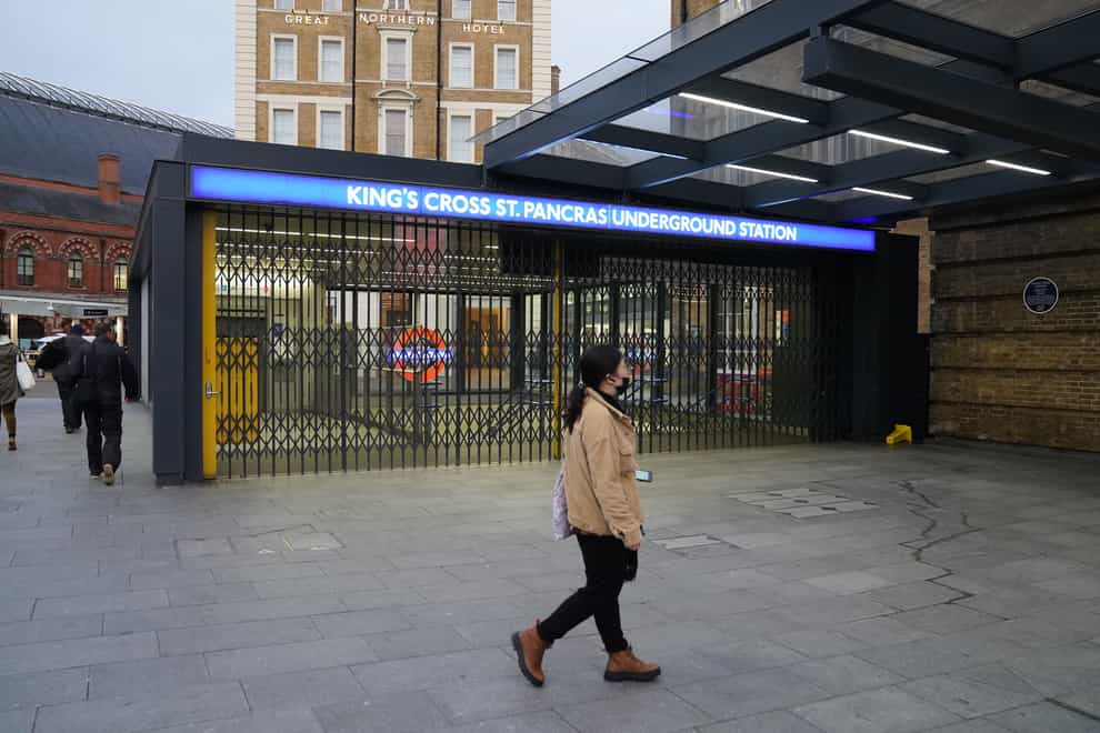 A woman walks past the closed shutters at the entrance to King’s Cross station (Stefan Rousseau/PA)