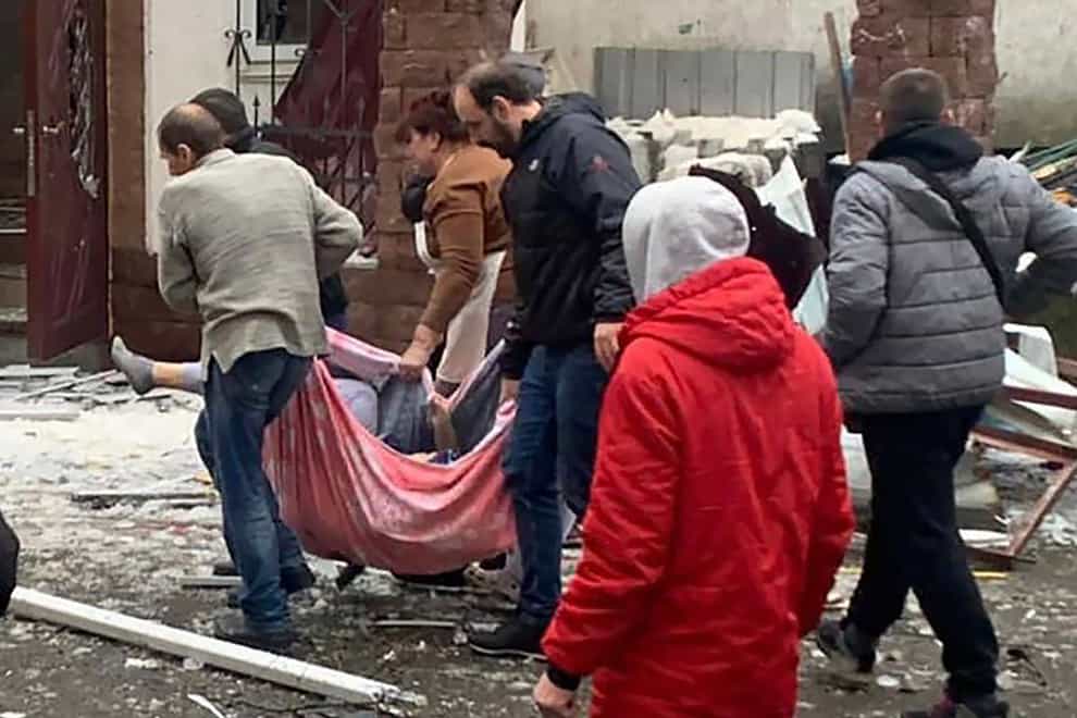 People carry a body at the scene of a Russian shelling in Kyiv (Kyiv Regional Police via AP)