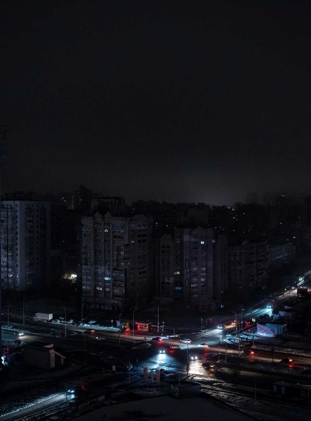 Cars drive past blacked out residential blocks after a Russian rocket attack in Kyiv (AP Photo/Evgeniy Maloletka)