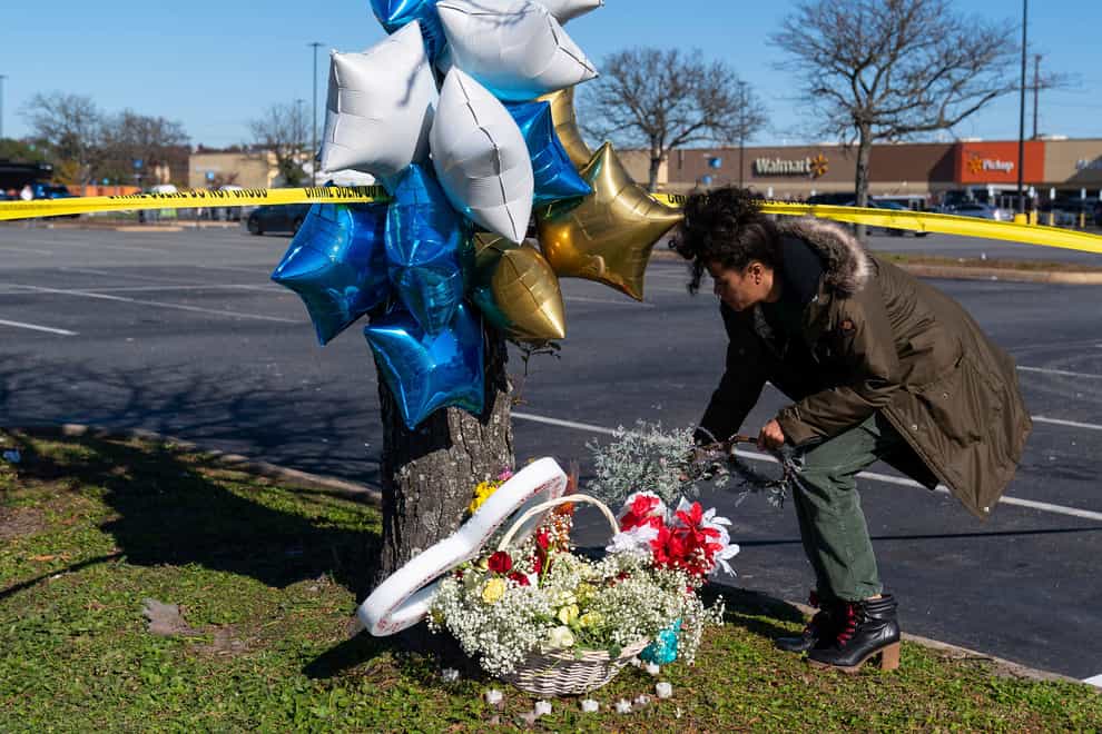 A passer-by places flowers near the Walmart store where six people were shot dead (AP Photo/Alex Brandon)