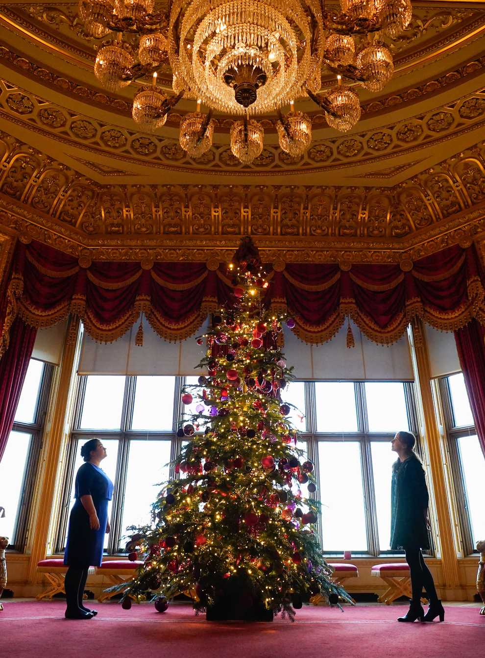 Members of the Royal Collection Trust look up at a Christmas tree on display in the Crimson Drawing Room (Andrew Matthews/PA)