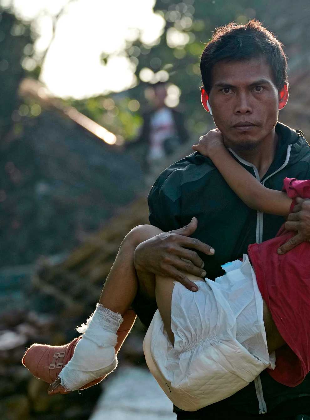 A man carries his injured daughter as they head to a temporary shelter for those displaced by Monday’s earthquake in Cianjur, West Java (AP)