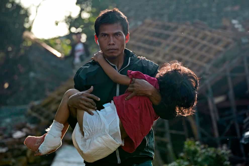 A man carries his injured daughter as they head to a temporary shelter for those displaced by Monday’s earthquake in Cianjur, West Java (AP)