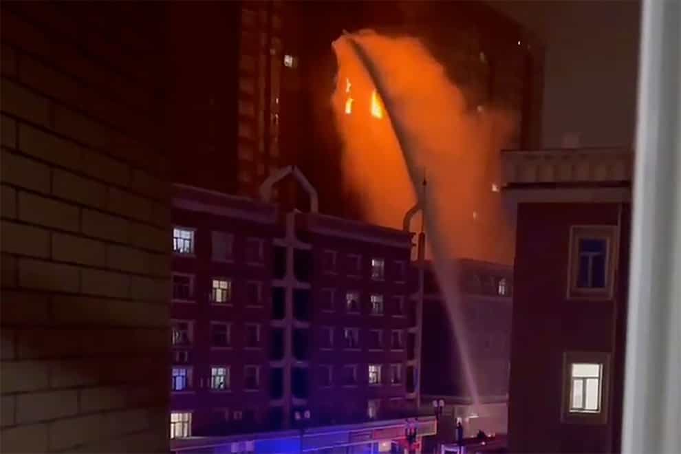 Firefighters spray water on a fire at a residential building in Urumqi in western China’s Xinjiang Uyghur Autonomous Region (AP)