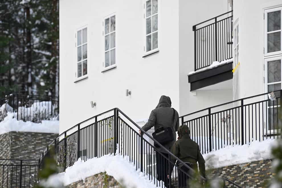 Two unidentified people are seen approaching a house where the Swedish security service allegedly arrested two people on suspicion of espionage in a predawn operation in Stockholm on Tuesday (Fredrik Sandberg/TT News Agency/AP)