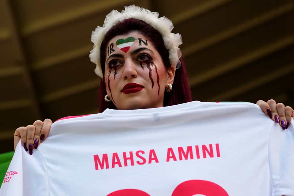 A woman holds a shirt with the name of Mahsa Amini, a woman who died while in police custody in Iran at the age of 22, as she takes her place in the stands ahead of the World Cup group B soccer match between Wales and Iran at the Ahmad Bin Ali Stadium in Al Rayyan, Qatar (Pavel Golovkin/AP)