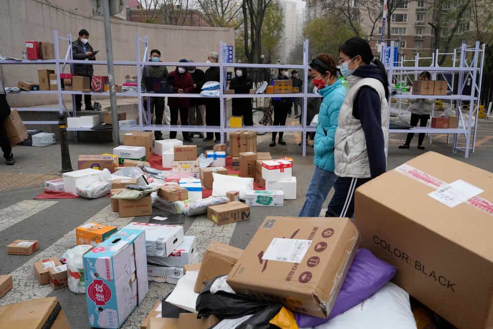 Residents wait for their deliveries behind shelves outside a community in Beijing (Ng Han Guan/AP)