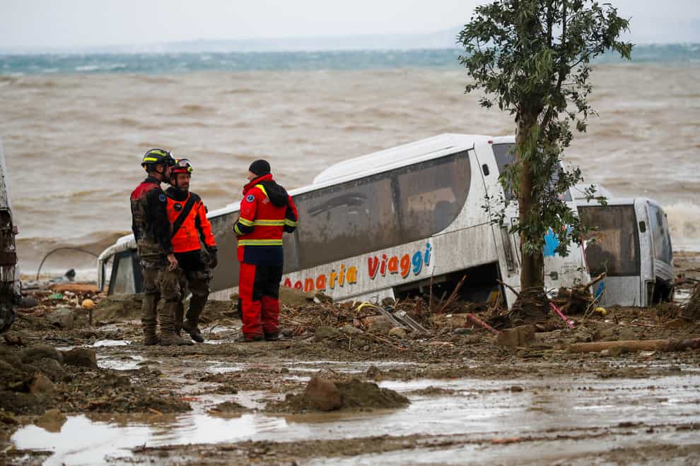 Rescuers stand next to a bus carried away after heavy rainfall triggered landslides on the southern Italian island of Ischia, Italy (Salvatore Laporta/AP)