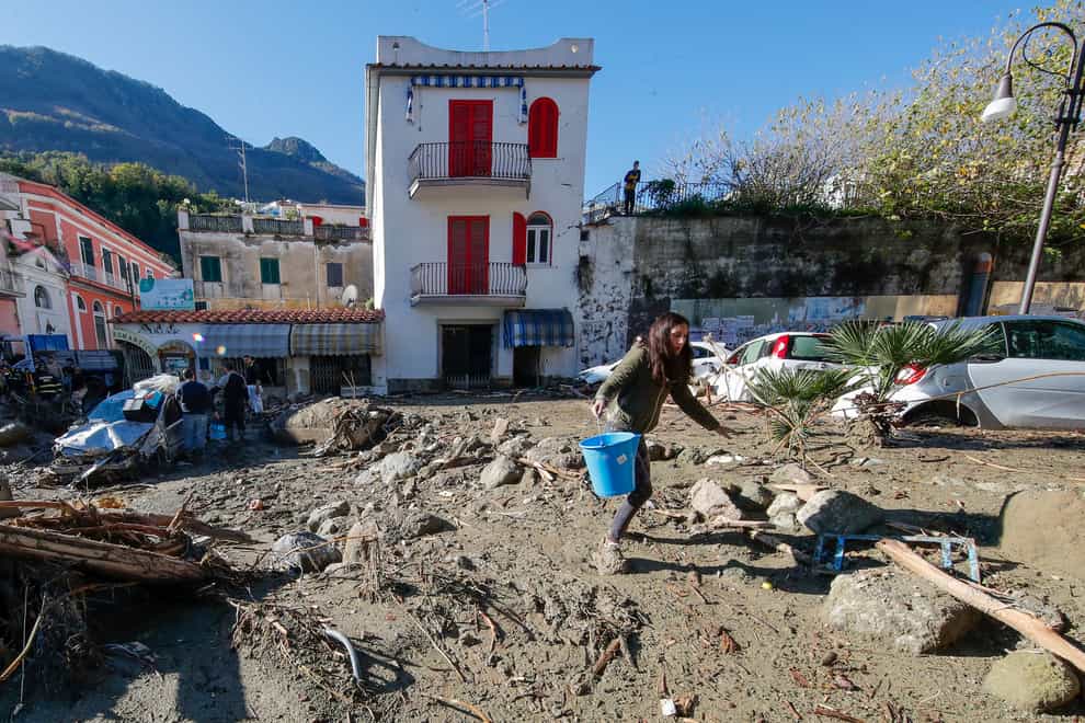 People remove mud and debris after heavy rainfall triggered a massive landslide (Salvatore Laporta/AP)