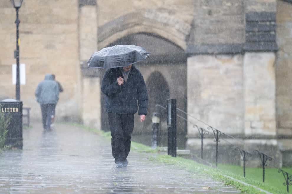 A man shelters under an umbrella as he walks in the rain near Wells Cathedral, Wells, Somerset (James Manning/PA)
