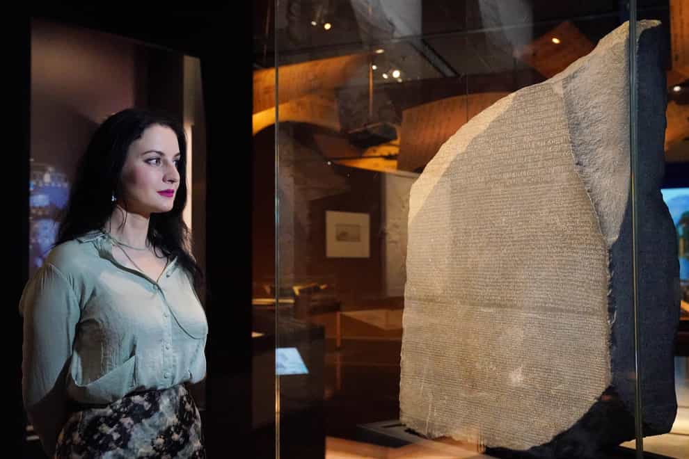 A member of staff observes the Rosetta Stone (Jonathan Brady/PA)