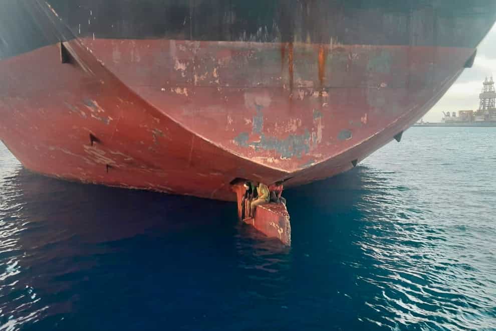 The three men perched on the rudder of an oil tanker anchored in the port of the Canary Islands, Spain (Salvamento Maritimo via AP)