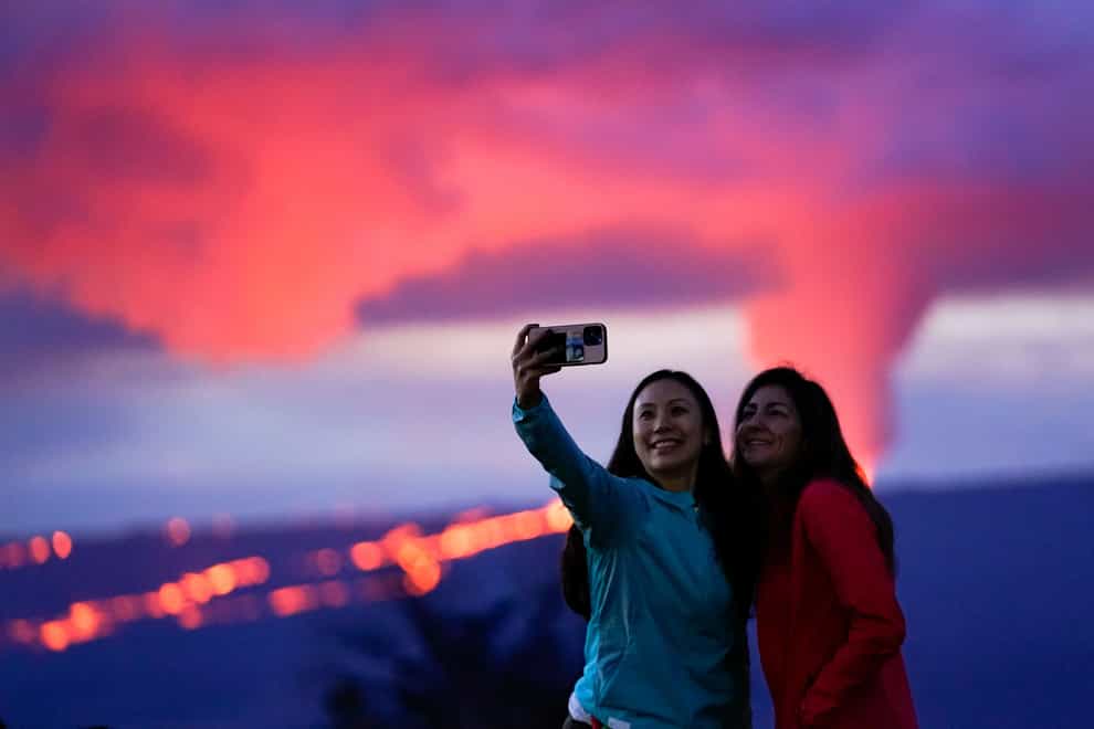 Ingrid Yang, left, and Kelly Bruno, both of San Diego, take a photo in front of lava erupting from Hawaii’s Mauna Loa volcano (Gregory Bull/AP)