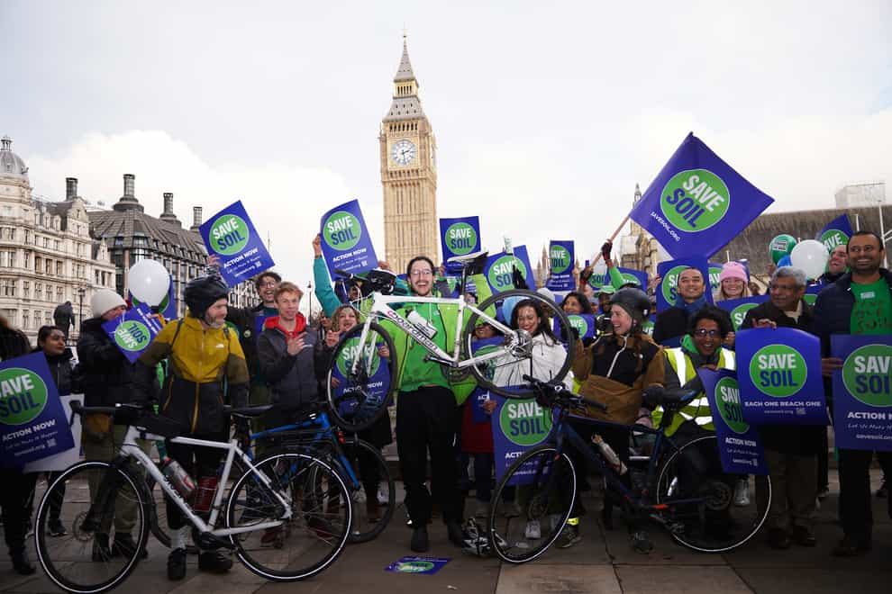 Oscar Smith (centre, holding bike), 17, was welcomed by a group of Save Soil protesters in Parliament Square (Yui Mok/PA)
