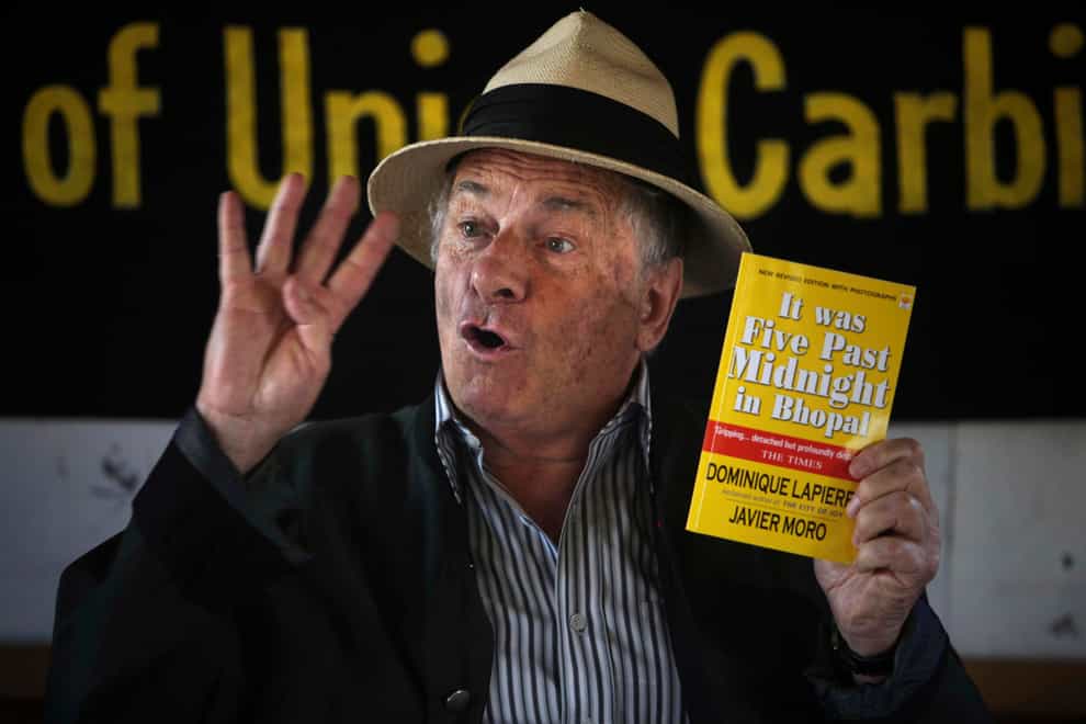 French writer and activist Dominique Lapierre holds a copy of his book on the Bhopal gas tragedy, in Bhopal, India, in 2009 (Altaf Qadri/AP)