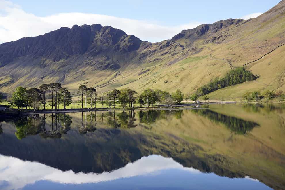Trees are reflected in the water at Buttermere in the Lake District (Owen Humphreys/PA)