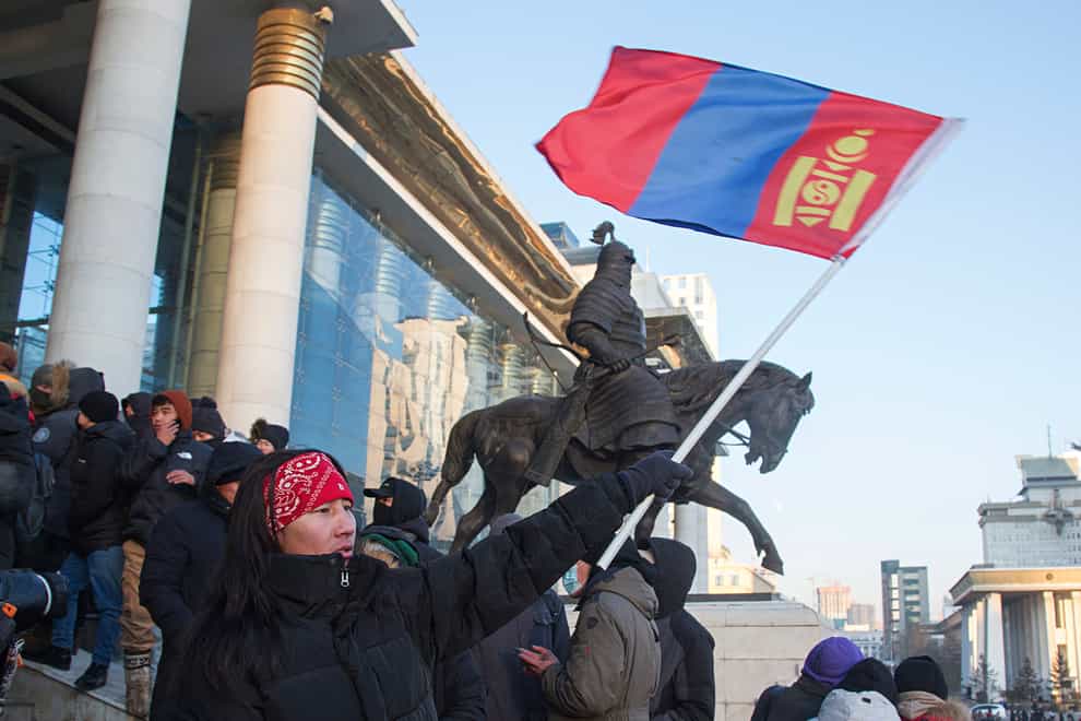 A protester waves a Mongolian national flag as protesters gather on the steps of the State Palace in Ulaanbaatar (AP)