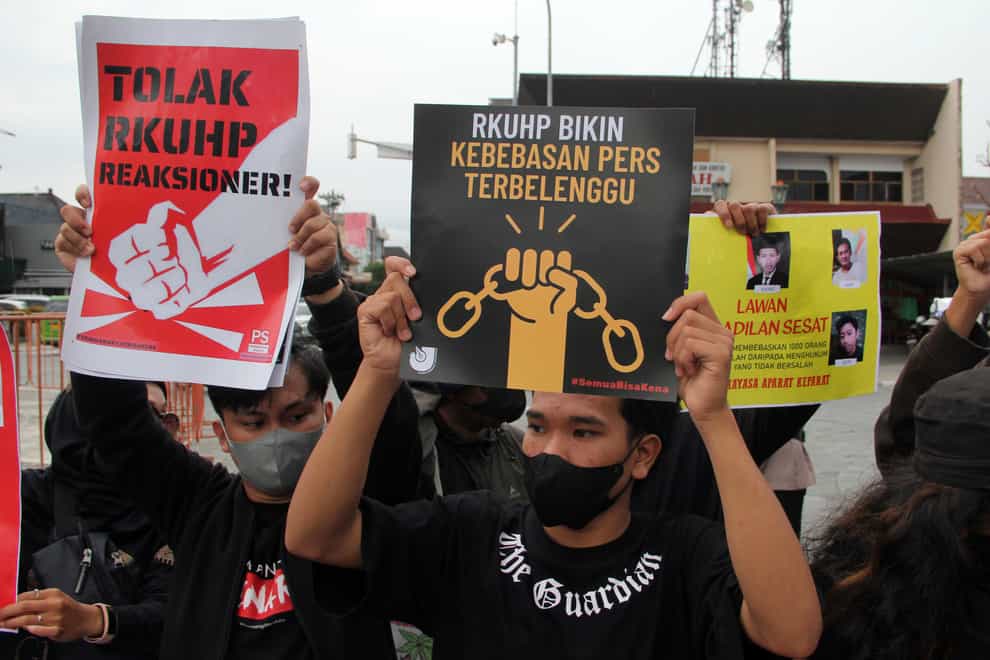 Activists hold up posters during a rally against Indonesia’s new criminal law (AP)