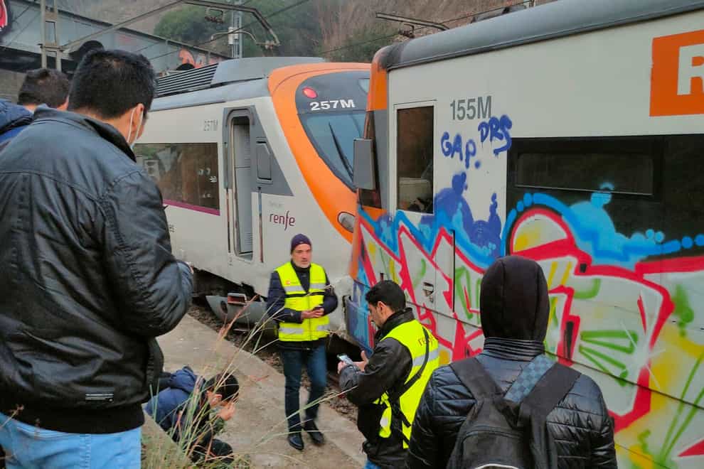 Passengers and railway staff are seen at the scene of a train collision in Montcada i Reixac (Josep Jorge via AP)