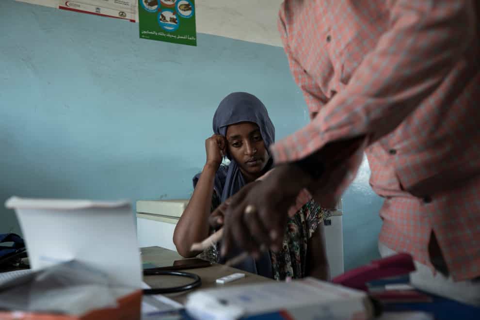 Surgeon and doctor-turned-refugee, Dr Tewodros Tefera, prepares a malaria test for 23-year-old Tigrayan refugee Hareg from Mekele, Ethiopia, at the Sudanese Red Crescent clinic in Hamdayet, eastern Sudan, near the border with Ethiopia (Nariman El-Mofty/AP)