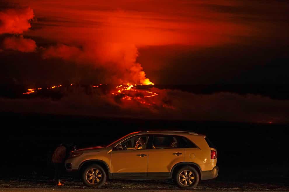 A man talks on a phone in his car alongside Saddle Road as the Mauna Loa volcano erupts near Hilo, Hawaii (Gregory Bull/AP/PA)