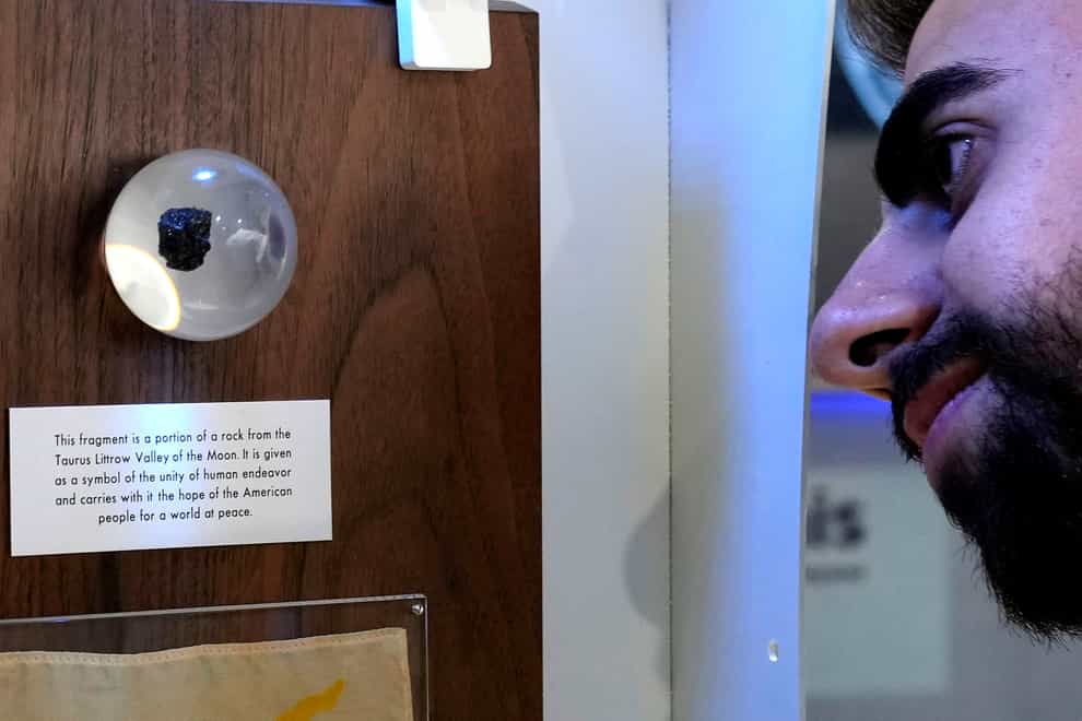A spectator looks at a tiny piece of moon rock encased in a plastic globe, on display at an exhibition commemorating the 50th anniversary of the last of the US manned missions to the moon and the Artemis spacecraft now orbiting the moon, in Nicosia, Cyprus (Petros Karadjias/AP/PA)