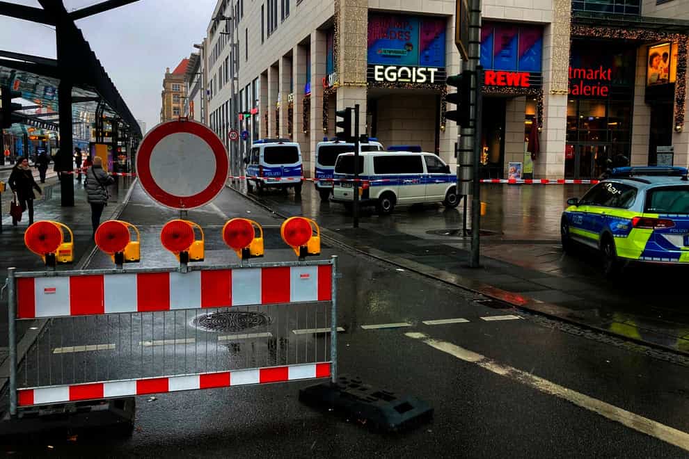 Police vehicles parked around a cordoned off area at the Altmarktgalerie after a hostage situation in Dresden, Germany ((Jorg Schurig/dpa via AP)