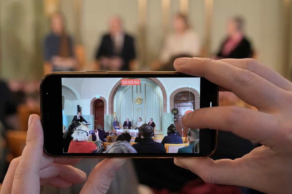 A journalist films representatives of the 2022 Nobel Peace Prize laureates, from left, Oleksandra Matviichuk, head of the Center for Civil Liberties, Jan Rachinsky, chairman of the International Memorial Board, Natallia Pinchuk, the wife of Nobel Peace Prize winner Ales Bialiatski and Norway Nobel Committee leader Berit Reiss-Andersen as they attend a press conference on the eve of the Nobel Peace Prize ceremony at the Norwegian Nobel Institute in Oslo, Friday Dec. 9, 2022. This year’s Nobel Peace Prize was shared by jailed Belarus rights activist Ales Bialiatski, the Russian group Memorial and the Center for Civil Liberties in Ukraine. (AP Photo/Markus Schreiber)