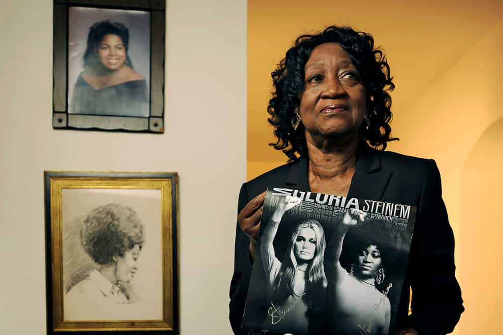 Dorothy Pitman Hughes poses at her Florida home in 2013, with a poster using a 1970s image of herself and Gloria Steinem (Bob Self/The Florida Times-Union/AP)