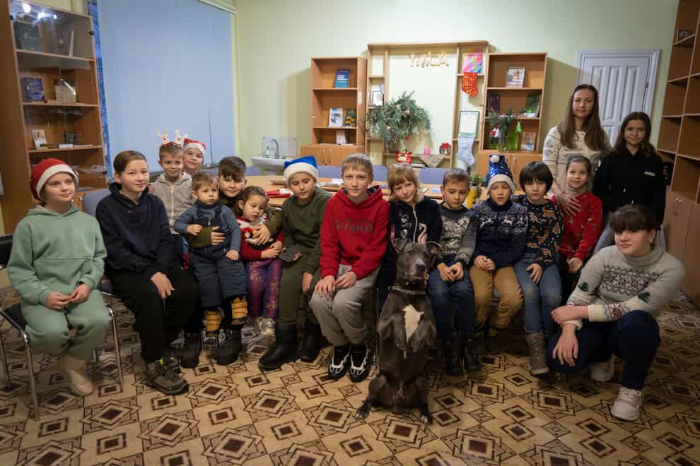 Children traumatised by the war in Ukraine pose for a photo with American pit bull terrier Bice at the Centre for Social and Psychological Rehabilitation in Boyarka, near Kyiv (Vasilisa Stepanenko/AP)