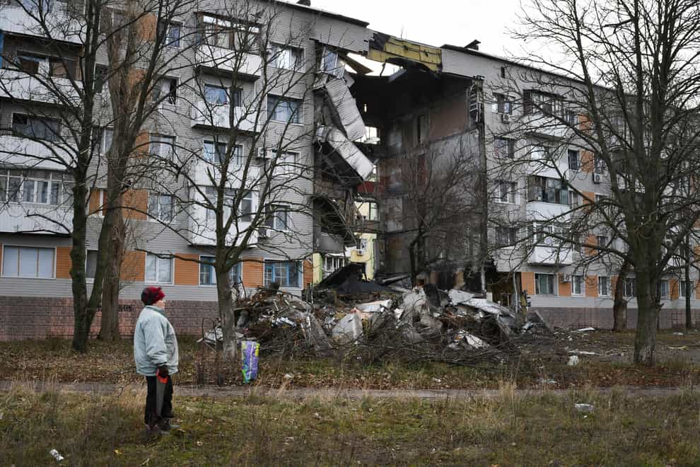 A woman passes by an apartment building damaged following by Russian shelling in Bakhmut in the Donetsk region, Ukraine (Andriy Andriyenko/AP)