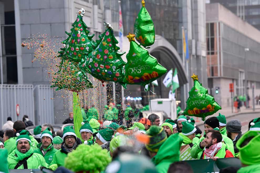 Union workers wear Christmas caps and wave balloons during a demonstration in Brussels (Geert Vanden Wijngaert/AP)
