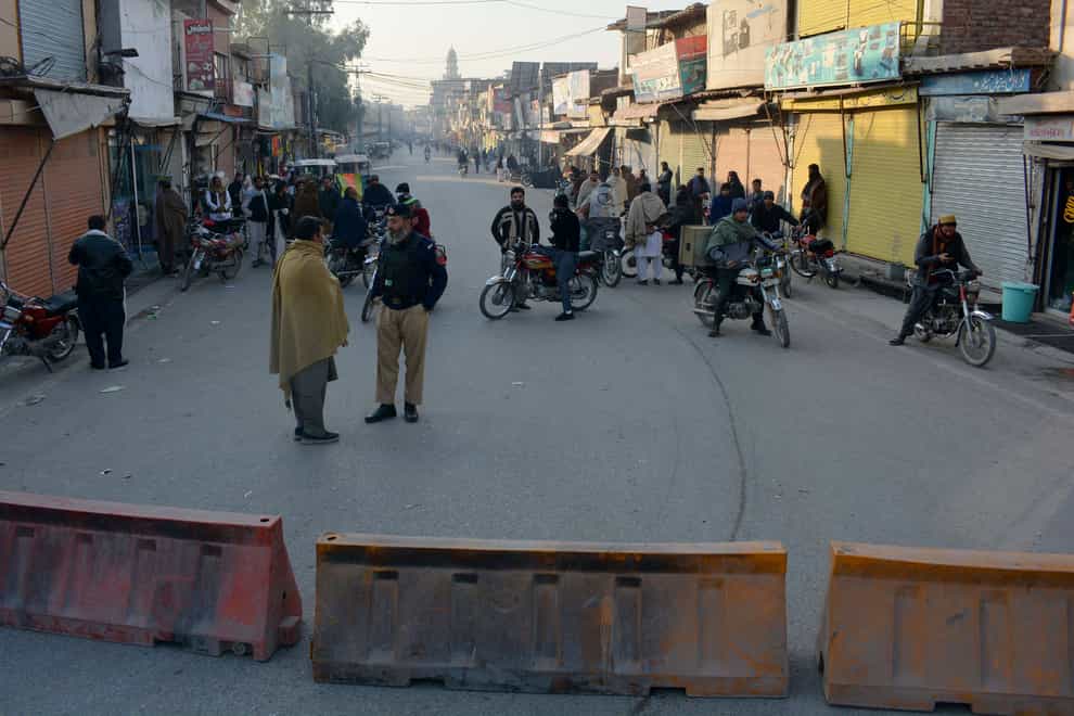 Security officials stand guard on a blocked road leading to a counter-terrorism centre where several Pakistani Taliban detainees have taken police officers and others hostage (AP)