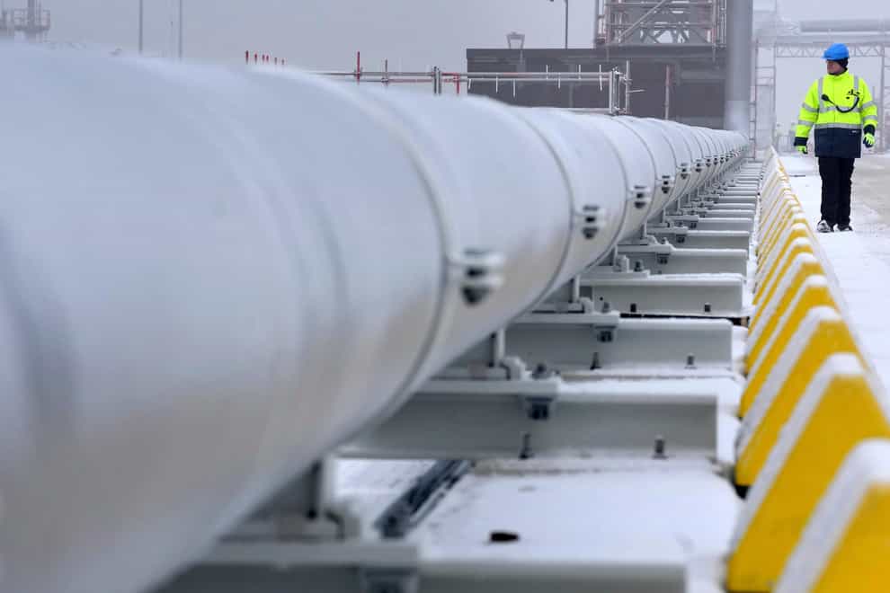 A worker walks past a gas tube that connects the ‘Hoegh Esperanza’ Floating Storage and Regasification Unit (FSRU) with main land during the opening of the LNG (Liquefied Natural Gas) terminal in Wilhelmshaven, Germany (Michael Sohn/AP/PA)