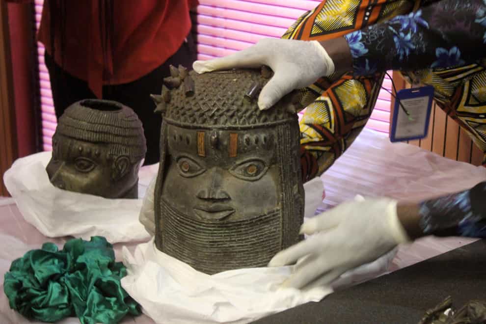 Benin bronzes looted in the past and returned to Nigeria are examined during a handing over ceremony in Abuja, Nigeria, Tuesday, December 20, 2022 (Olamikan Gbemiga/AP/PA)