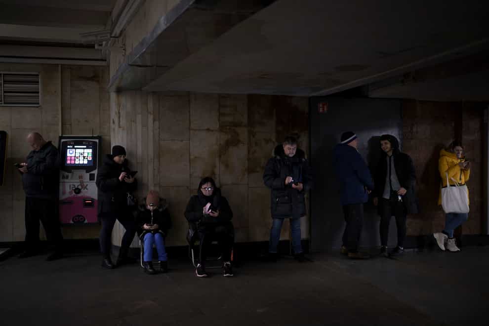 People use their phones while they gather in a metro station during an air raid alarm in Kyiv, Ukraine (Felipe Dana/AP)