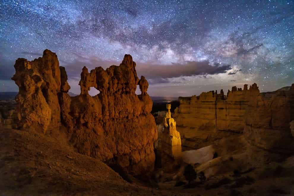 A hoodoo with small windows and Thor’s Hammer against a night sky with clouds and the Milky Way below Sunset Point in ryce Canyon National Park, Utah (Alamy/PA)