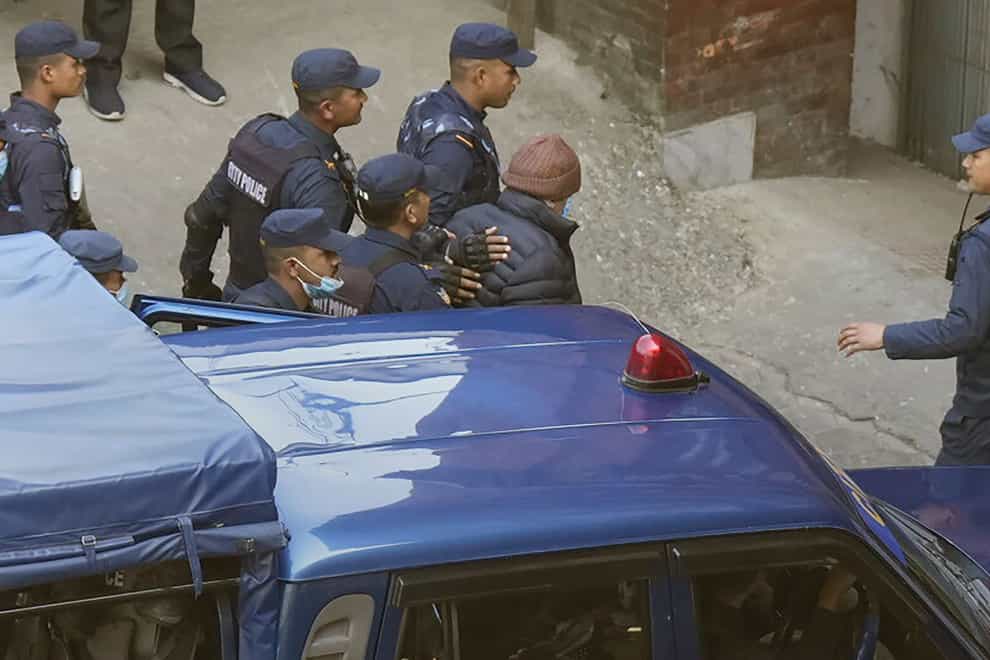 Nepalese police escort Charles Sobhraj, in brown cap, to the immigration office, in Kathmandu, Nepal, Friday, Dec. 23, 2022. Confessed French serial killer Charles Sobhraj has been released from prison in Nepal after serving most of his sentence. Sobhraj was driven out of Central Jail in Kathmandu to the Department of Immigration under heavy guard Friday after the Supreme Court ordered him to be released because of poor health and good behavior. (AP Photo/Niranjan Shrestha)