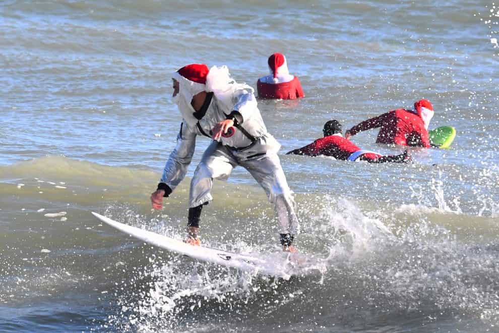 Surfer Corey Howell in a space man Surfing Santa suit, rides with waves with other surfing Santas for the 14th annual Surfing Santas of Cocoa Beach event Christmas Eve morning (Malcolm Denemark/Florida Today via AP/PA)
