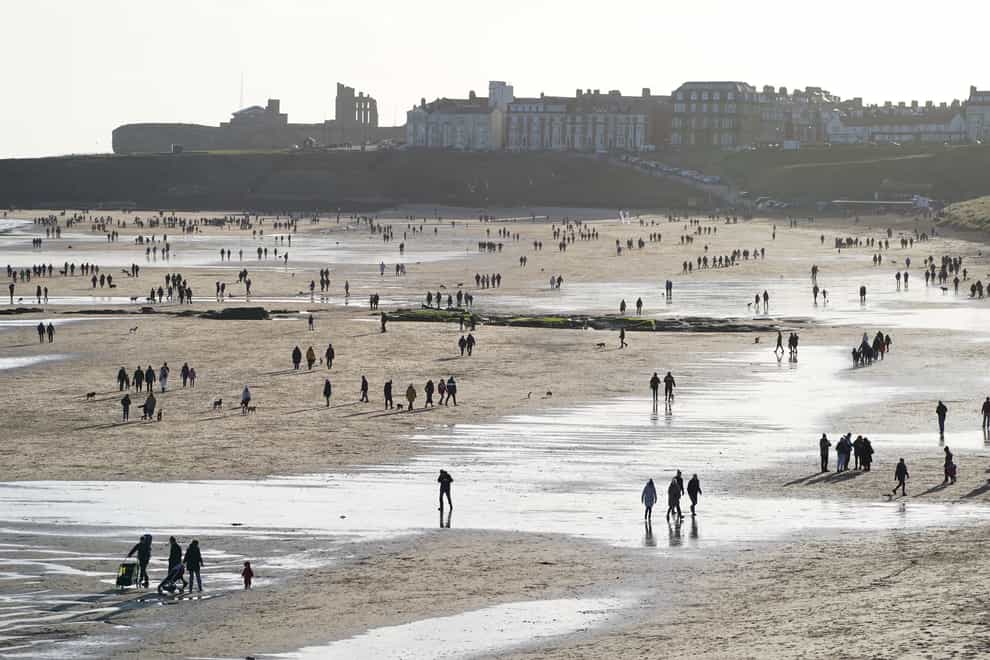 People walk along Tynemouth Longsands Beach in Tynemouth in the north-east of England (/PA)