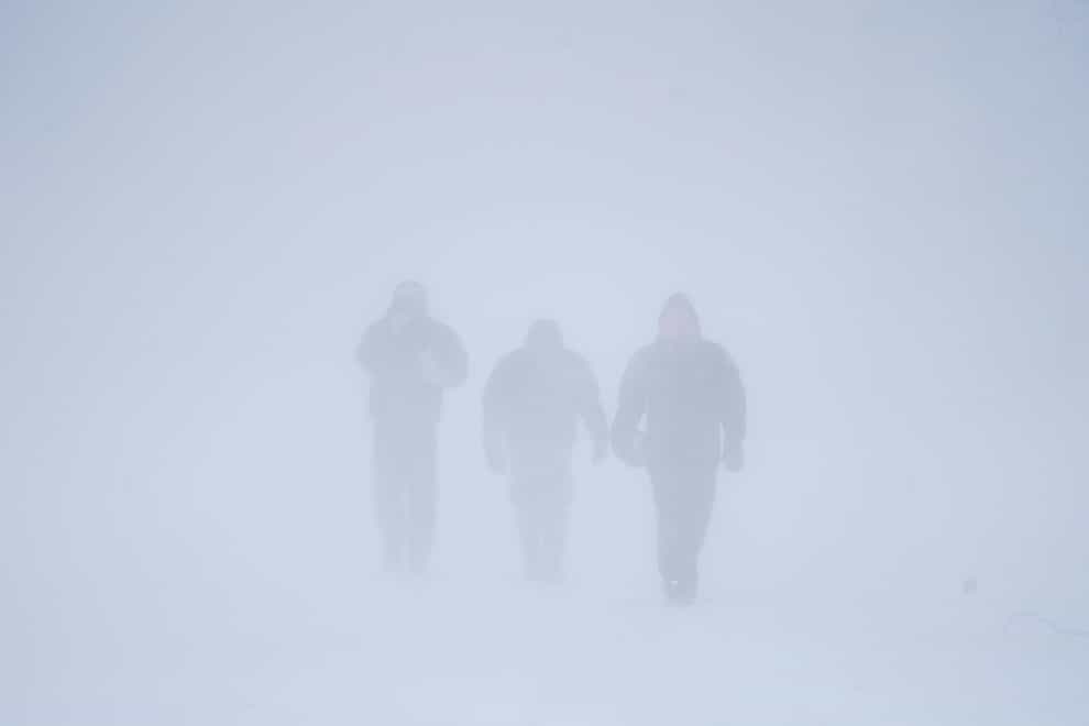 Three men walk down Richmond Avenue in whiteout conditions during a sustained blizzard in Buffalo, New York, on Saturday December 24 2022 (Derek Gee/The Buffalo News/AP)