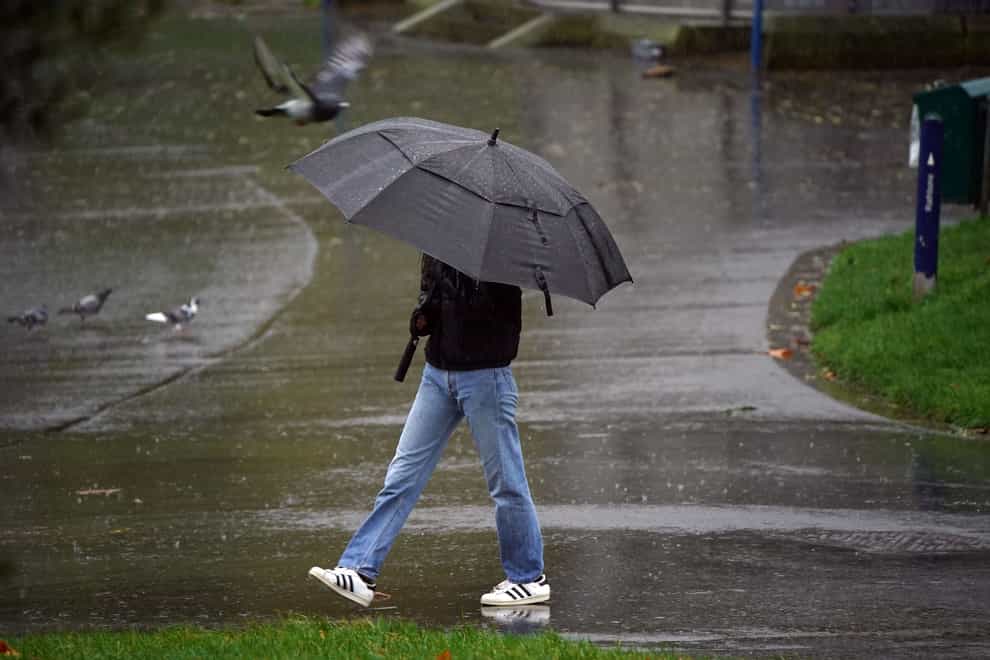 A man holds an umbrella in heavy rain Peter Byrne(/PA)